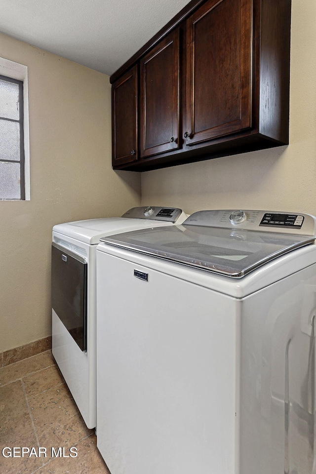 washroom with cabinet space, stone finish flooring, baseboards, and separate washer and dryer