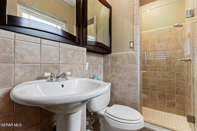 full bathroom featuring toilet, a stall shower, tile walls, and wainscoting