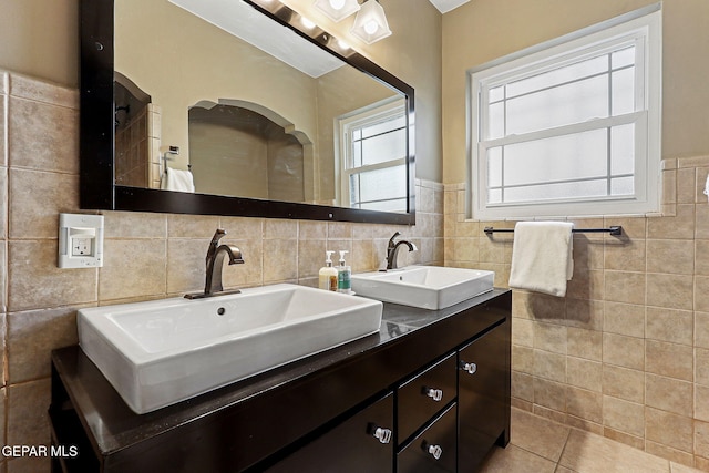 bathroom with tile patterned flooring, a sink, tile walls, and double vanity