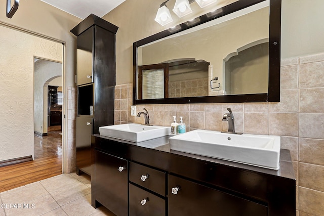 full bath featuring double vanity, tile patterned flooring, a sink, and tile walls