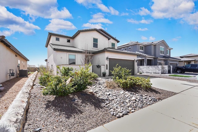 view of front of property featuring a garage, concrete driveway, a tiled roof, central AC, and stucco siding