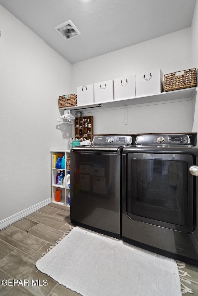 laundry area featuring visible vents, washing machine and dryer, wood finished floors, laundry area, and baseboards