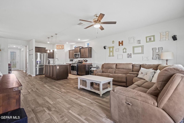 living room featuring a ceiling fan, visible vents, and wood finished floors