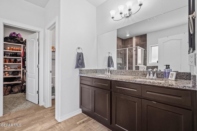 bathroom with double vanity, a shower stall, a spacious closet, and a sink