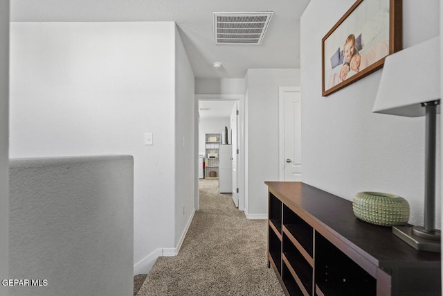 hallway featuring carpet floors, baseboards, and visible vents