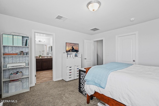 carpeted bedroom with ensuite bath and visible vents