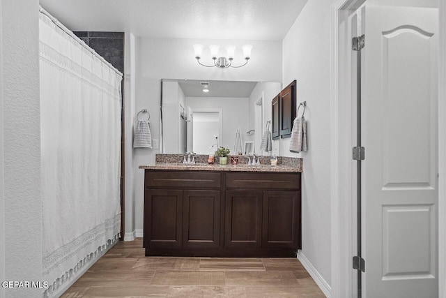 full bathroom with baseboards, a chandelier, wood finish floors, and vanity