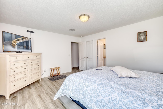 bedroom with a textured ceiling, visible vents, and light wood-style floors