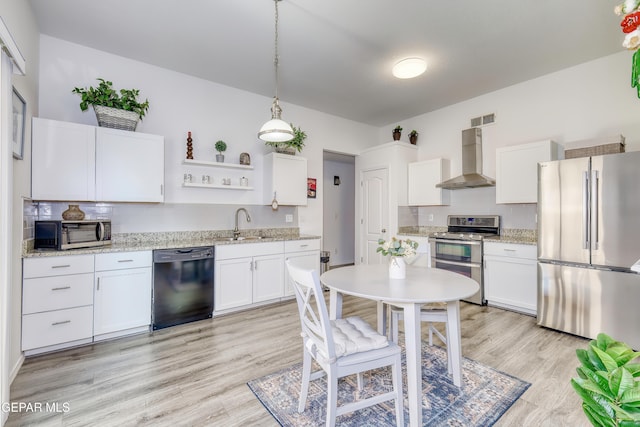 kitchen featuring visible vents, wall chimney exhaust hood, stainless steel appliances, light wood-style floors, and white cabinetry