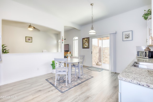 dining space with light wood-type flooring, arched walkways, and baseboards