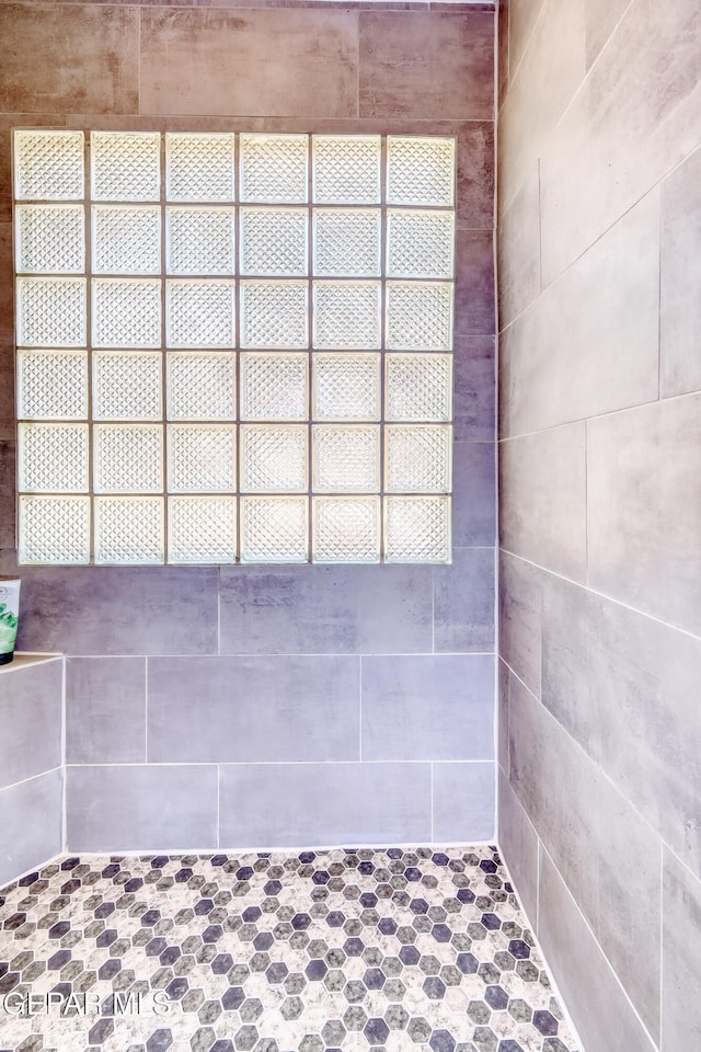 full bathroom with tiled shower and a wealth of natural light