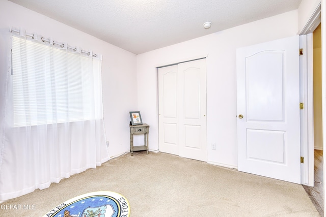 unfurnished bedroom featuring a textured ceiling, a closet, and carpet