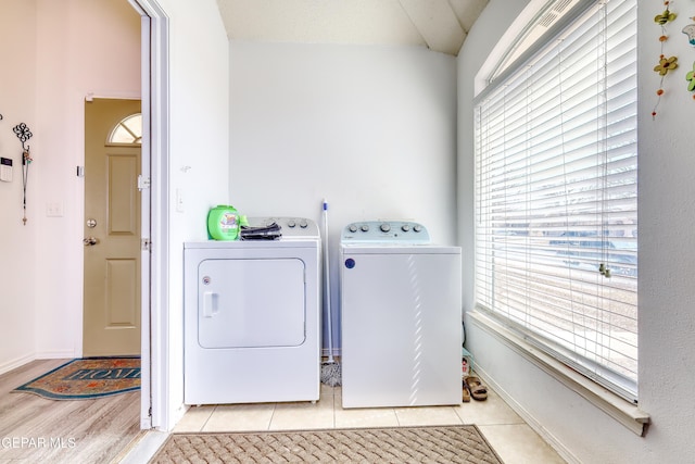 laundry room featuring laundry area, light tile patterned floors, a wealth of natural light, and washing machine and clothes dryer