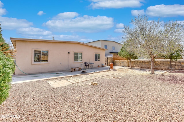 rear view of property with stucco siding, fence, and a patio