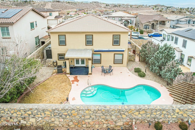 rear view of house featuring stucco siding, a tile roof, a patio, a residential view, and a fenced in pool