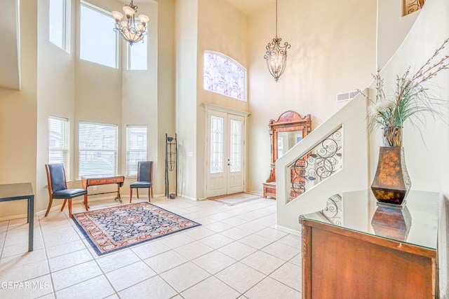 foyer featuring visible vents, light tile patterned floors, a healthy amount of sunlight, a chandelier, and stairs