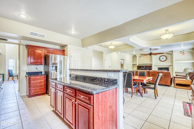 kitchen with dark brown cabinets, light tile patterned flooring, visible vents, and a kitchen island