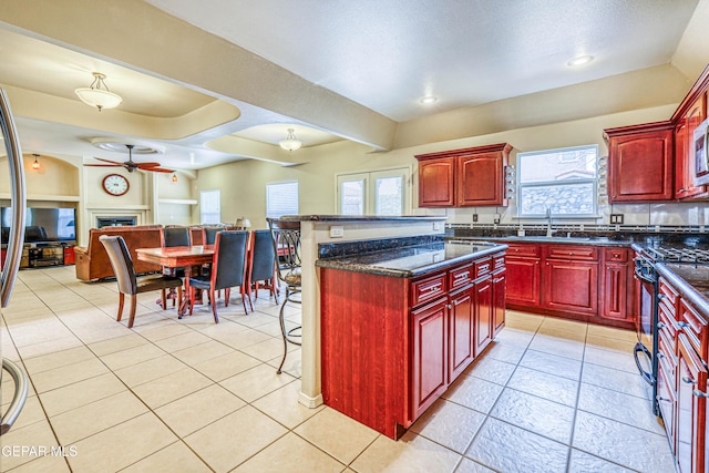 kitchen featuring range with gas cooktop, dark brown cabinets, open floor plan, and a fireplace