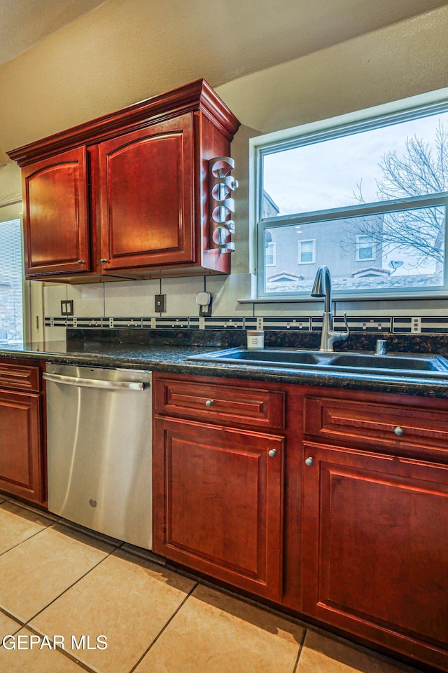 kitchen featuring a sink, dark stone counters, light tile patterned floors, dark brown cabinets, and dishwasher