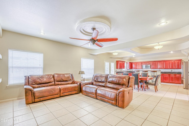 living room featuring baseboards, plenty of natural light, light tile patterned flooring, and a ceiling fan