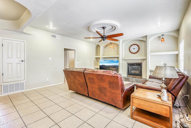 living room featuring light tile patterned floors, visible vents, and built in shelves