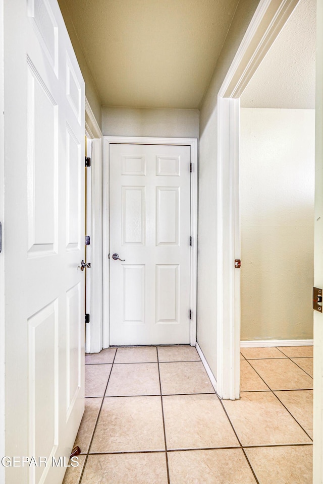 hall with light tile patterned flooring and baseboards