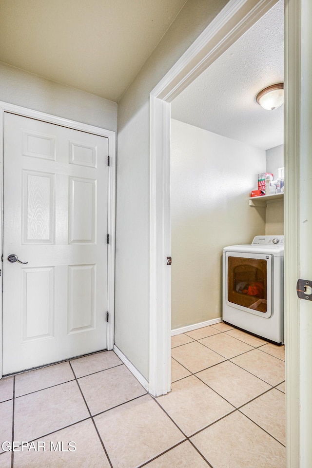 clothes washing area featuring baseboards, light tile patterned floors, laundry area, a textured ceiling, and separate washer and dryer