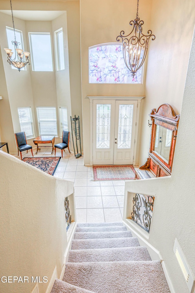 foyer featuring tile patterned flooring, a chandelier, stairs, french doors, and a high ceiling