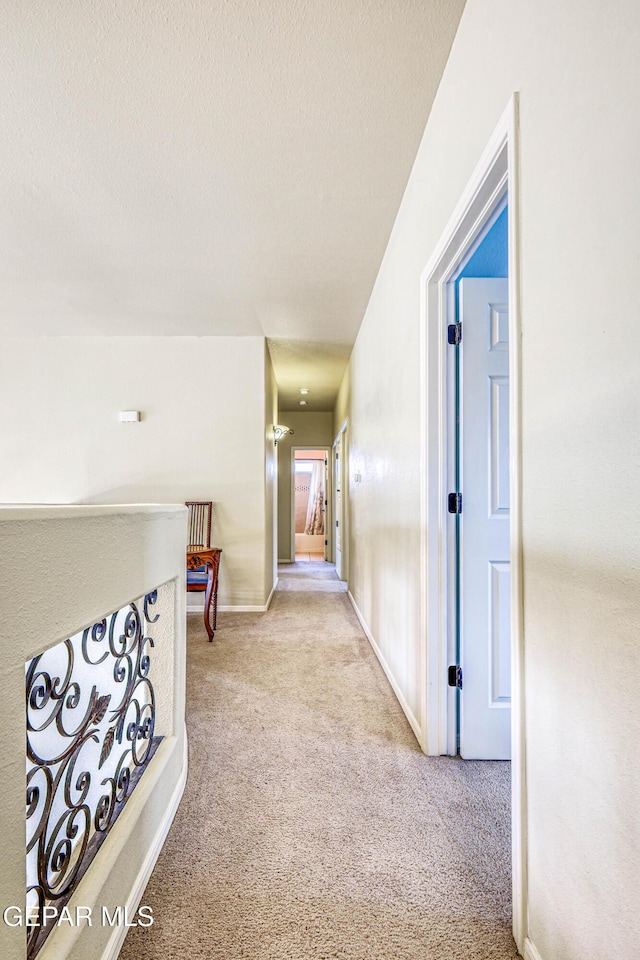 corridor with baseboards, a textured ceiling, and carpet