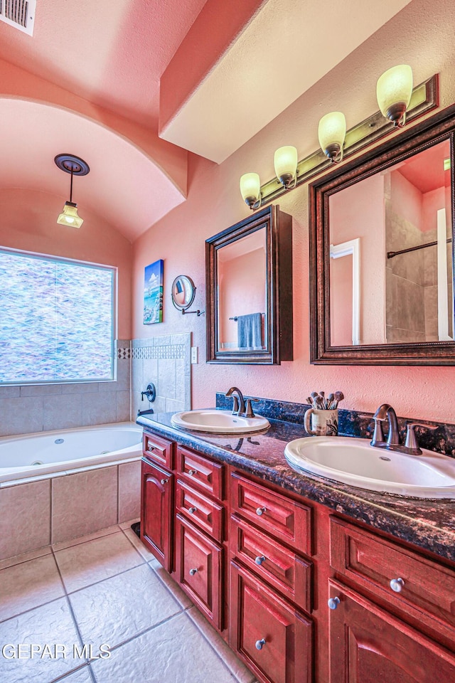 bathroom featuring tiled bath, visible vents, lofted ceiling, and a sink