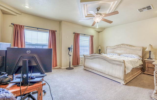 bedroom featuring light carpet, visible vents, multiple windows, and ceiling fan