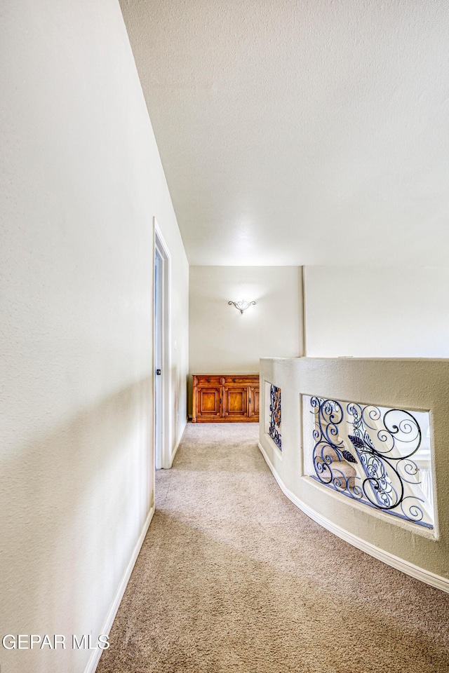 unfurnished living room featuring a textured ceiling, baseboards, and light carpet