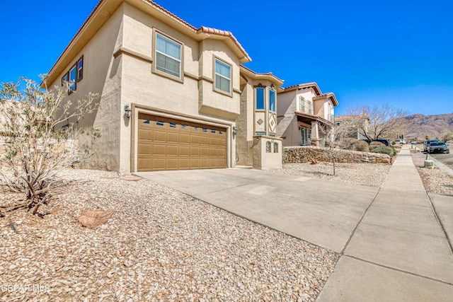 view of front of home with stucco siding, an attached garage, driveway, and a tiled roof