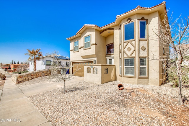 view of front facade with stucco siding, driveway, fence, an attached garage, and a tiled roof