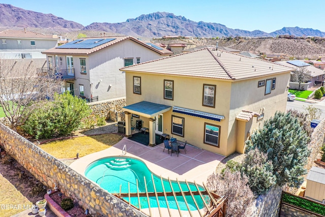 back of house with a fenced backyard, a mountain view, a tile roof, and a patio