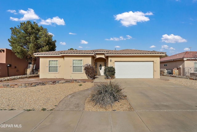 view of front facade with a garage, fence, a tile roof, concrete driveway, and stucco siding