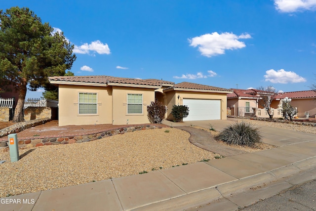 view of front of home featuring a garage, fence, driveway, a tiled roof, and stucco siding