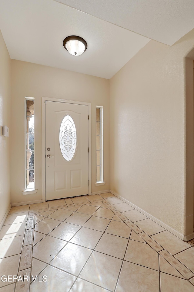 foyer entrance featuring light tile patterned flooring and baseboards