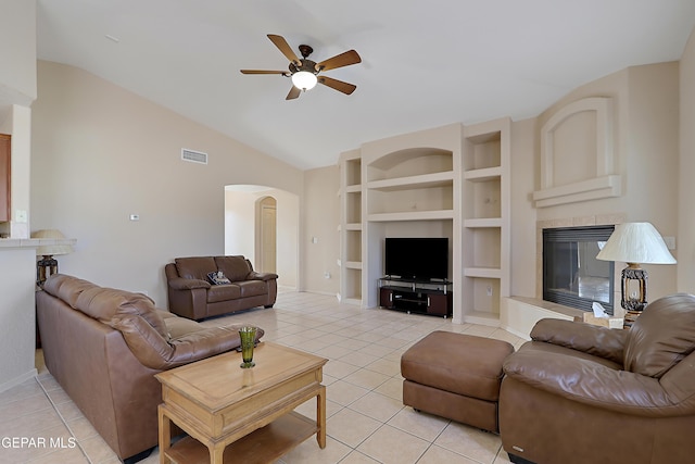 living room with built in features, visible vents, arched walkways, a tiled fireplace, and light tile patterned flooring