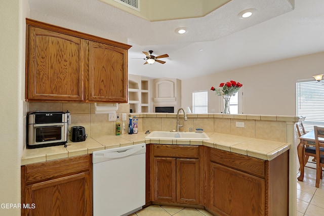 kitchen with a peninsula, tasteful backsplash, white dishwasher, and a sink