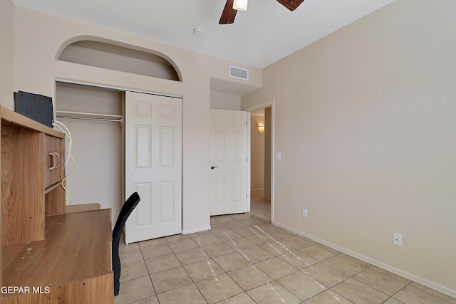 unfurnished bedroom featuring light tile patterned floors, a ceiling fan, visible vents, baseboards, and a closet