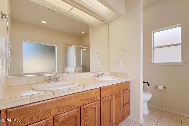 bathroom with a stall shower, a sink, toilet, and tile patterned floors