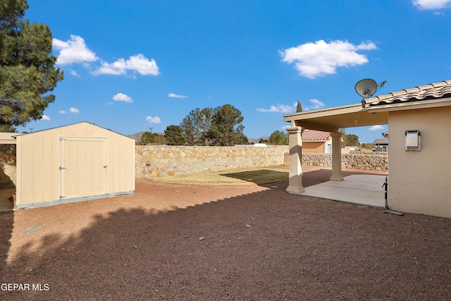 view of yard featuring an outbuilding, a patio area, fence, and a shed