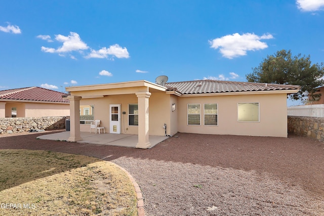 rear view of property featuring a patio area, a tile roof, fence, and stucco siding