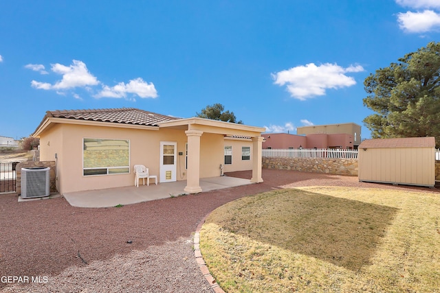 rear view of house featuring stucco siding, central air condition unit, fence, a shed, and an outdoor structure