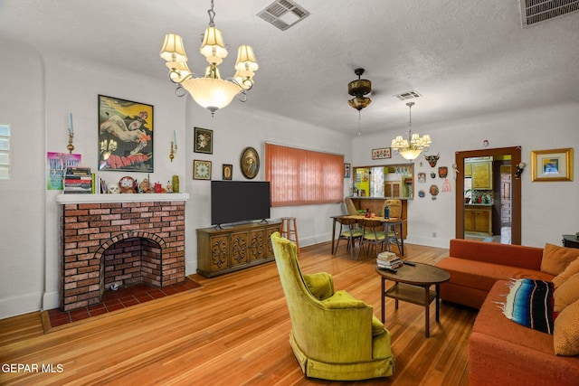 living room with a brick fireplace, visible vents, and a chandelier