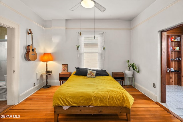 bedroom featuring light wood-style floors, ensuite bath, and baseboards