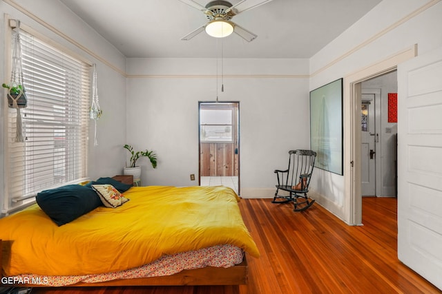 bedroom with ensuite bath, baseboards, and wood finished floors