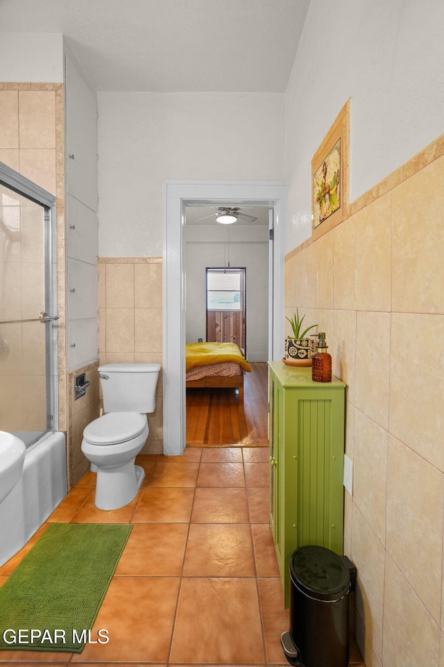 full bath with enclosed tub / shower combo, tile patterned flooring, toilet, tile walls, and ensuite bath