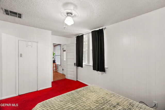 bedroom featuring a textured ceiling, carpet, and visible vents